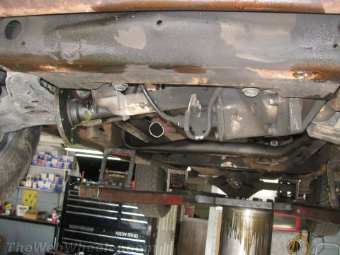 1987 Suzuki Samurai - Underside of a vehicle on a lift, revealing drivetrain and frame details.