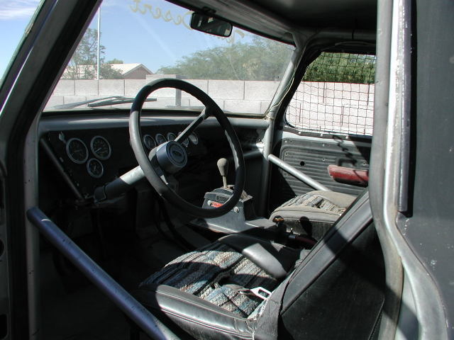 Truck interior with roll cage, aftermarket gauges, and worn seats
