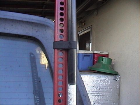 1990 Ford Bronco - A Hi-Lift jack is mounted to the exterior of a vehicle, with coolers and other items visible in the background.