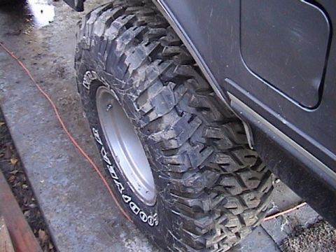 1990 Ford Bronco - Close-up of a large, off-road tire mounted on a dark-colored vehicle.