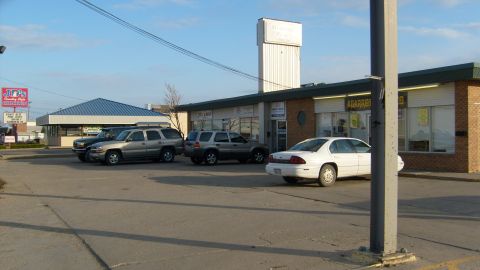 1995 Ford C-350 (Centurion Conversions) - Several vehicles are parked in front of commercial buildings under a clear sky.