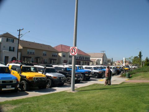2007 Toyota FJ Cruiser - A row of Toyota FJ Cruisers, including a yellow model in the foreground, are parked under a clear blue sky.