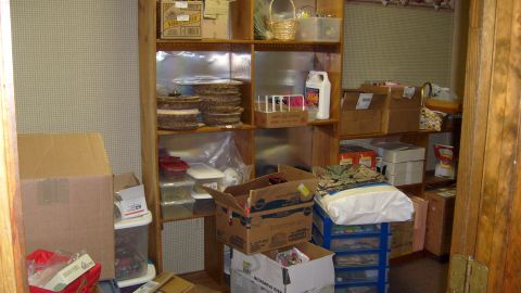 1995 Ford C-350 (Centurion Conversions) - A cluttered room features shelves packed with various items, including boxes, baskets, and plastic containers, suggesting storage or a pant…