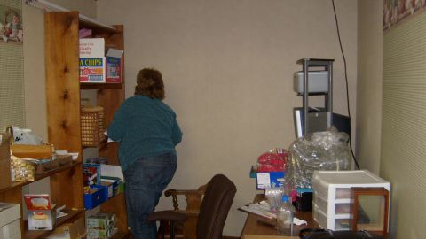 1995 Ford C-350 (Centurion Conversions) - A woman is seen organizing items on shelves in a room filled with various storage containers and boxes.