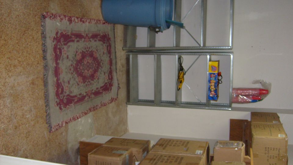 Interior storage area with shelves holding a blue barrel, rug, and boxes