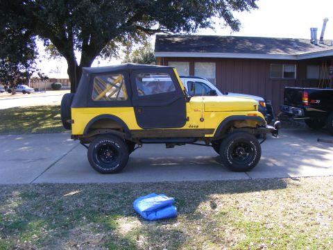 1981 Jeep CJ7 - This yellow 1981 Jeep CJ7 is parked in a driveway with a black soft top and doors.