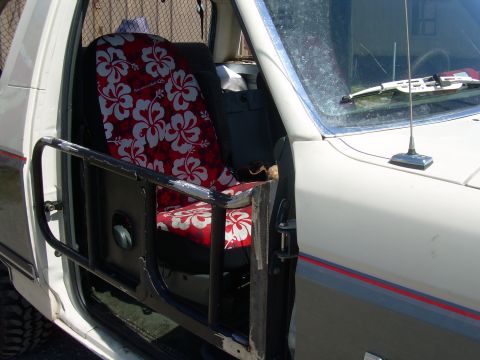 1991 Ford Bronco - The interior of a vehicle features custom seat covers with a tropical flower pattern and a protective metal bar on the door.