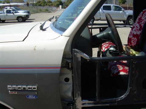 1991 Ford Bronco - The 'Bronco XLT' badge and Ford logo are visible on the door panel of this 1991 Ford Bronco, which also shows its interior with Hawaiian-pa…