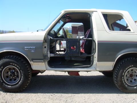 1991 Ford Bronco - Driver's side door of a 1991 Ford Bronco, open to reveal the interior and a protective cage.