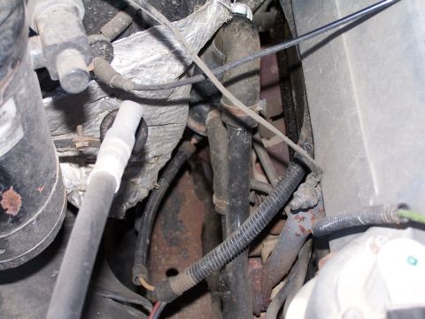 1990 Ford Bronco - Close-up view of an engine compartment, showing various hoses, wires, and metal parts.