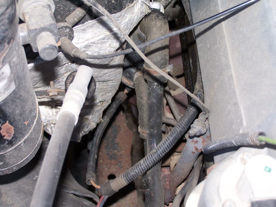 Engine compartment with hoses, wires, and rusted metal components