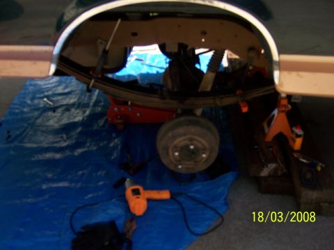1991 Ford Bronco - Vehicle's rear suspension is elevated for maintenance, with tools and a blue tarp visible on the ground.