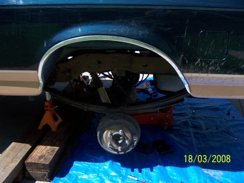 1991 Ford Bronco - The rear suspension of a vehicle is shown, lifted on jack stands for maintenance.