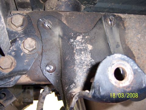 1991 Ford Bronco - Close-up of a rusty vehicle suspension bracket, showing bolts and metal components.
