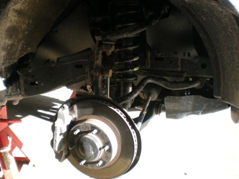 2007 Toyota Land Cruiser - Close-up view of the front suspension and brake system of a vehicle.