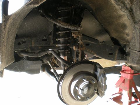 2007 Toyota Land Cruiser - Close-up of a vehicle's front suspension and braking system, with a jack stand supporting the frame.