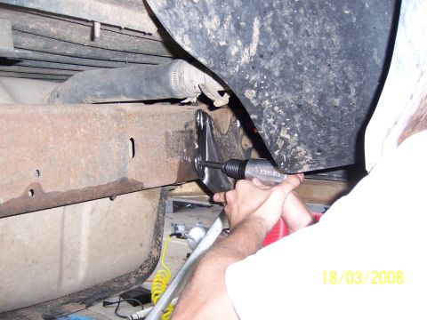 1991 Ford Bronco - Working on the frame of a vehicle, likely a truck or SUV, with an air hammer.