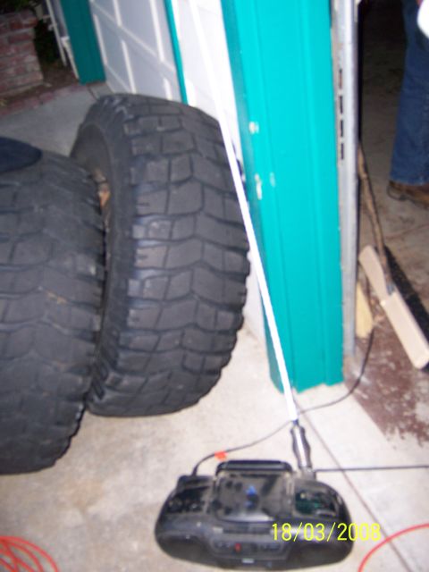 1991 Ford Bronco - Two large off-road tires are positioned near a teal garage door, with a boombox visible on the concrete floor.