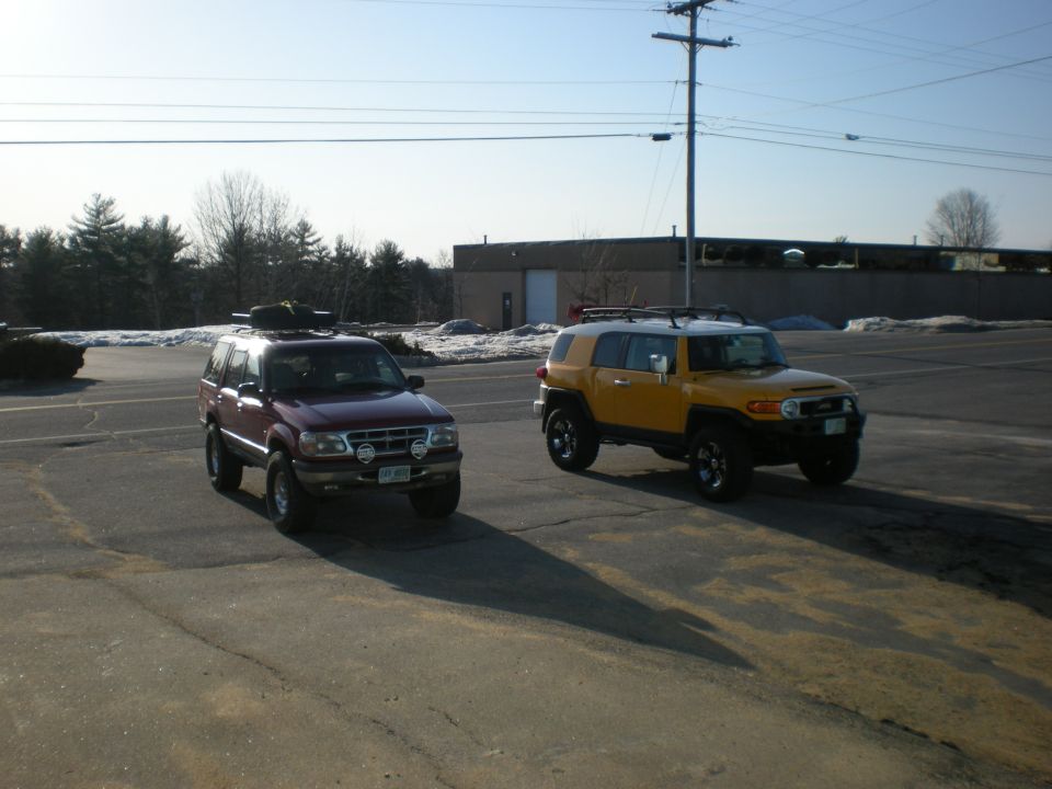 Yellow lifted Toyota FJ Cruiser parked beside a red lifted Ford Explorer in a snowy parking lot