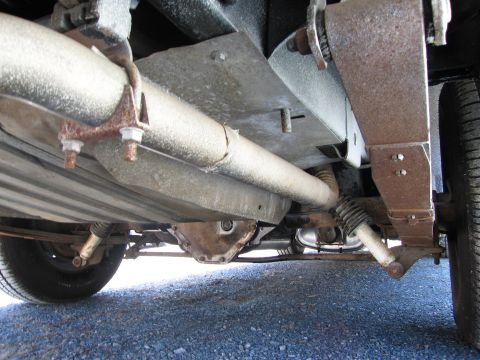 1991 Ford Crown Victoria LTD - The underside of a vehicle reveals its exhaust pipes, differential housing, and suspension components.