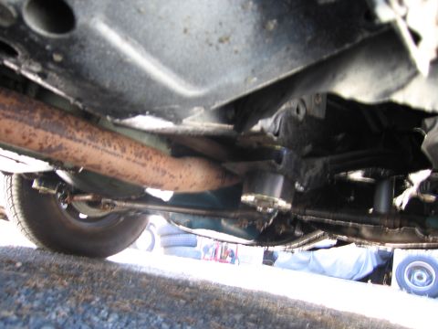 1991 Ford LTD Crown Victoria - The undercarriage of a vehicle is visible, with focus on the exhaust system and suspension parts.