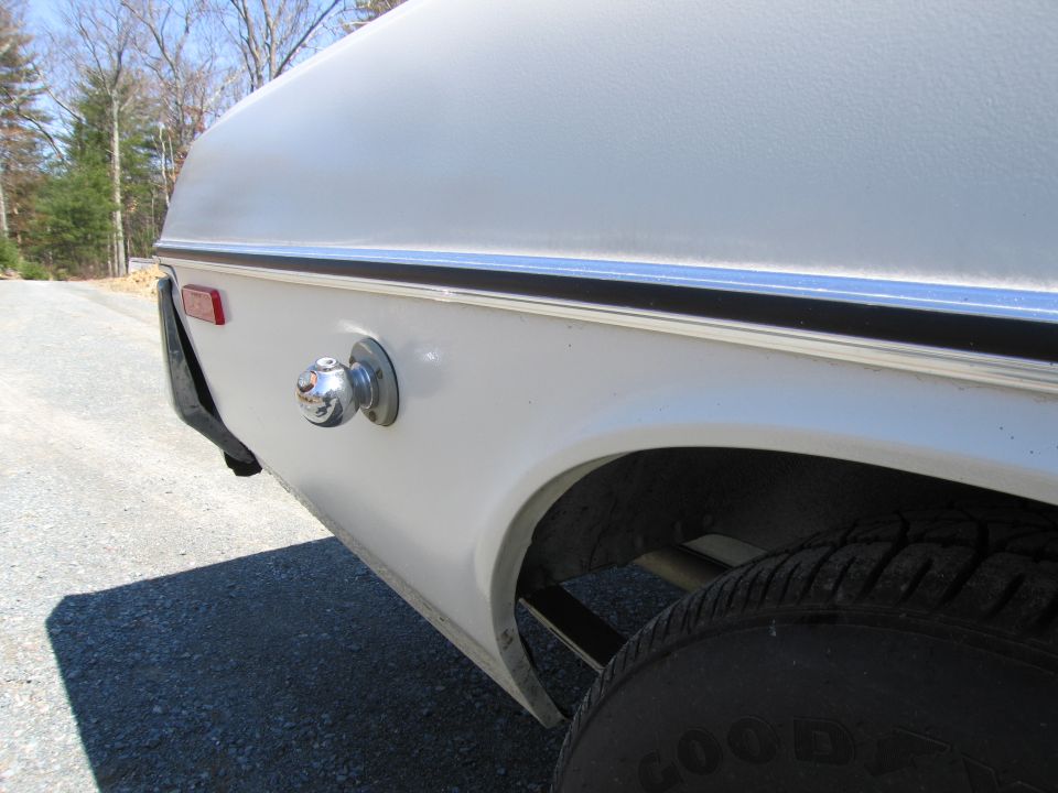 Trailer hitch ball mount on white vehicle exterior, rear quarter panel view