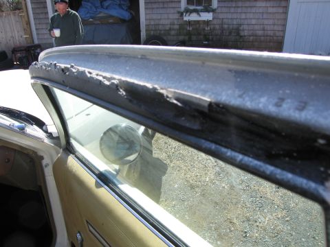 1991 Ford LTD Crown Victoria - Close-up of damaged metal trim around a car's window, with a person visible in the background.