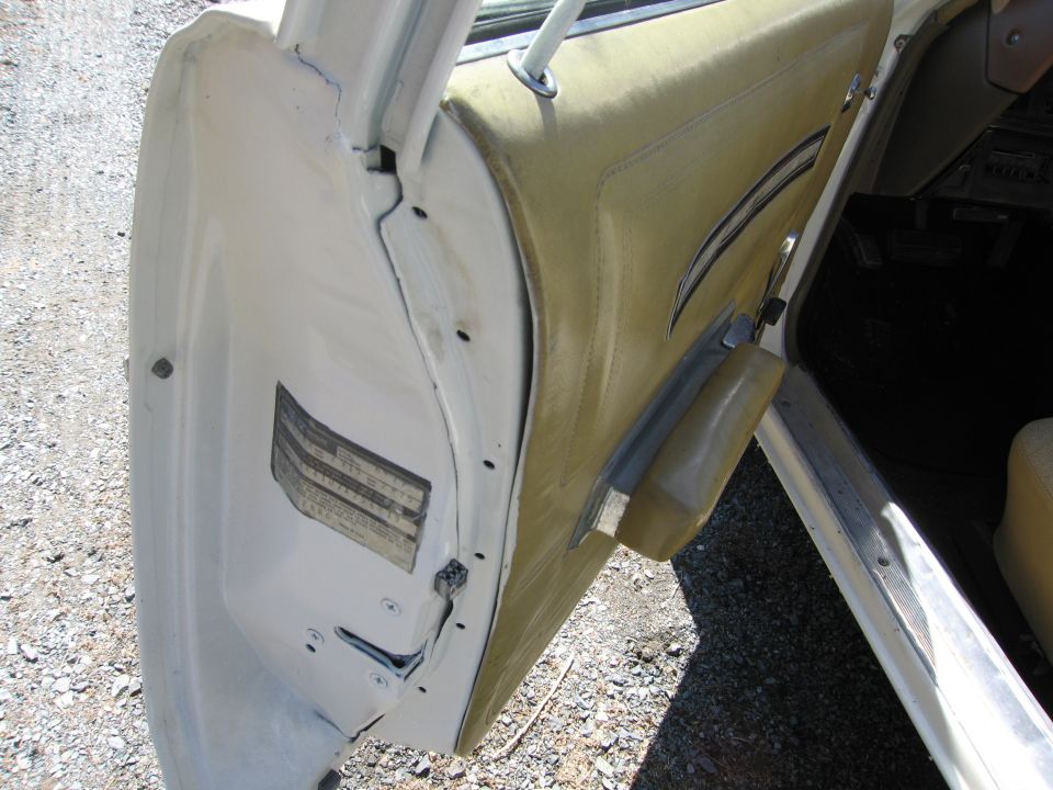 Interior of a car door showing the panel and latch mechanism. A sticker with text is visible on the door frame