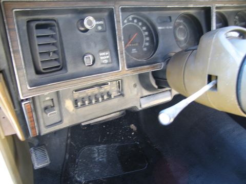 1991 Ford LTD Crown Victoria - Close-up of a car's dashboard shows an old radio and a vent, with a steering column on the right.