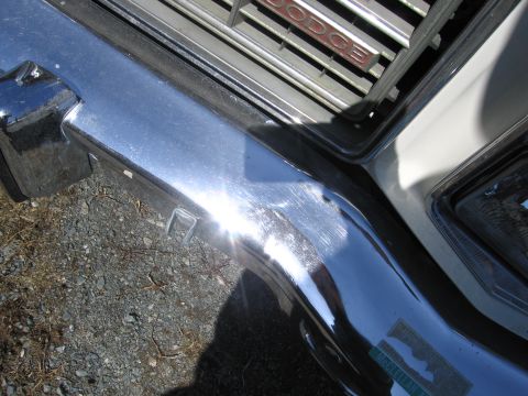 1991 Ford LTD Crown Victoria - Close-up of a chrome bumper and Dodge grille, showing some wear and a sticker.