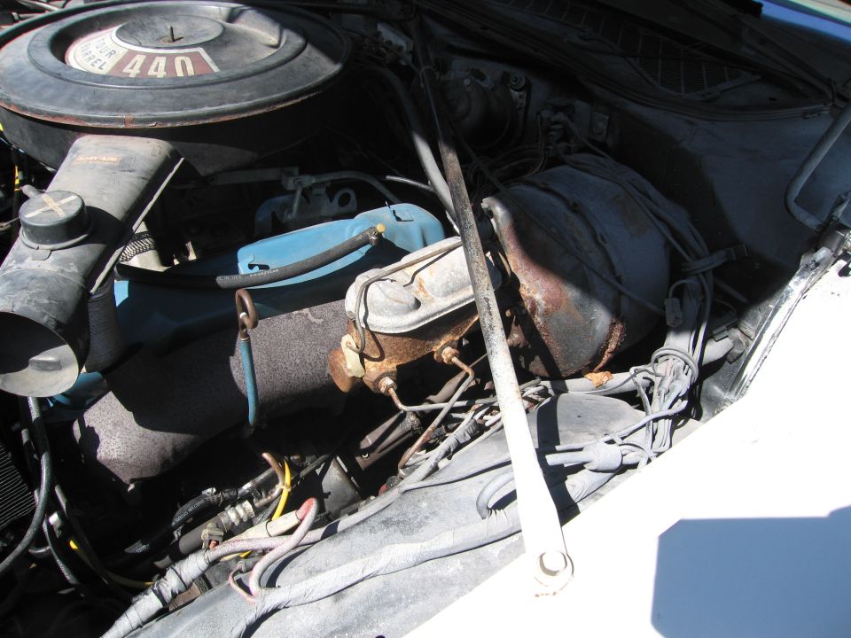 Engine bay with a black air cleaner labeled "440", blue fluid reservoir, and rusty brake master cylinder