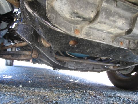 1991 Ford LTD Crown Victoria - Close-up of a vehicle's undercarriage, focusing on suspension and frame elements.