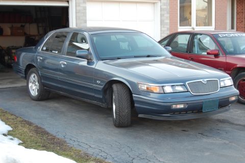 1985 Mercury Grand Marquis - Blue sedan parked in a driveway with snow on the ground.