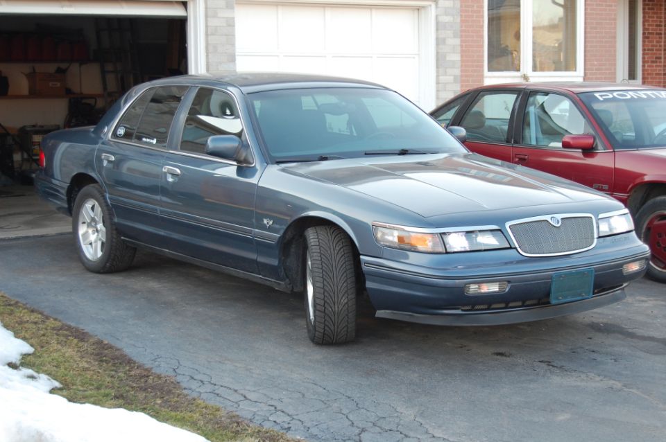 Blue-gray Mercury Grand Marquis sedan parked in driveway, front-right view