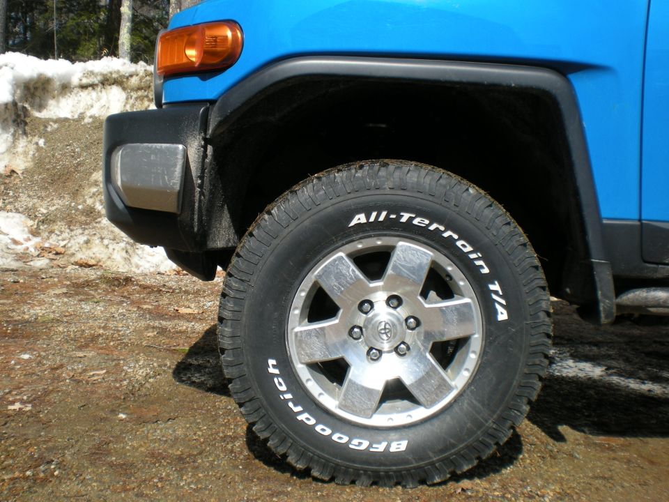 Front wheel of blue FJ Cruiser with BFGoodrich All-Terrain T/A tire on alloy wheel, snow in background