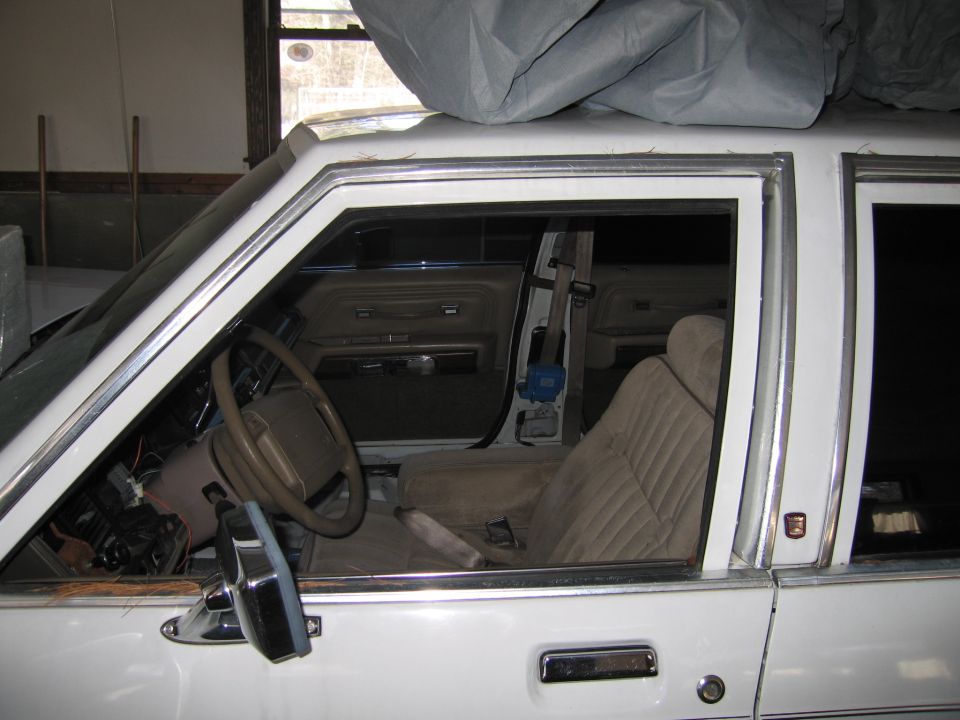 White 1990s sedan interior, tan seats, steering wheel, door panel visible