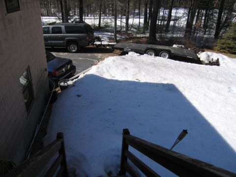 1991 Ford LTD Crown Victoria - A dark sedan and a grey SUV towing a trailer are parked in a snowy driveway next to a house.