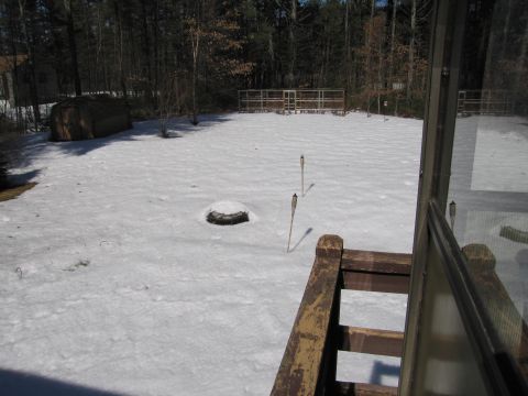 1991 Ford LTD Crown Victoria - A snowy backyard scene a shed, fence, and torches, with a view from a deck.