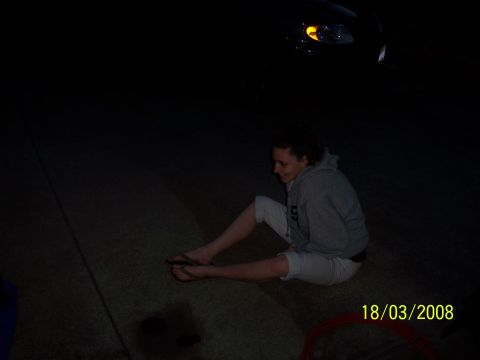 1991 Ford Bronco - A woman sits on the ground at night, with the front of a car visible in the background.