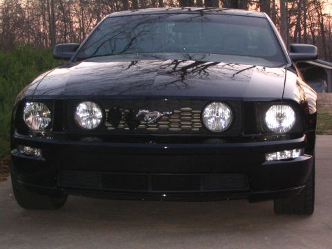 2007 Ford Mustang - The front of a black Ford Mustang is shown, its distinctive grille and headlights.