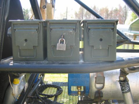 1992 Ford Mustang - Three olive drab ammo cans are secured to a metal rack, with one of them locked.