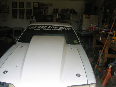 1992 Ford Mustang - A white 1992 Ford Mustang is parked in a garage, a prominent hood scoop and a "The Hot Rod Shop" decal on the windshield.