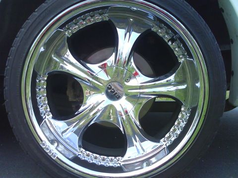 2003 Ford Crown Victoria - A close-up of a shiny chrome wheel with a custom design and visible tire tread.