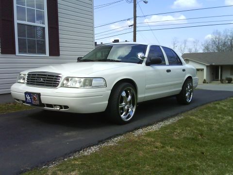 2003 Ford Crown Victoria - A white 2003 Ford Crown Victoria is parked in a driveway, custom chrome wheels and a clean body style.
