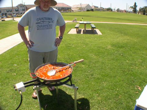 2007 Toyota FJ Cruiser - A man stands next to a large cooking pan in a park, with picnic tables and buildings in the background.