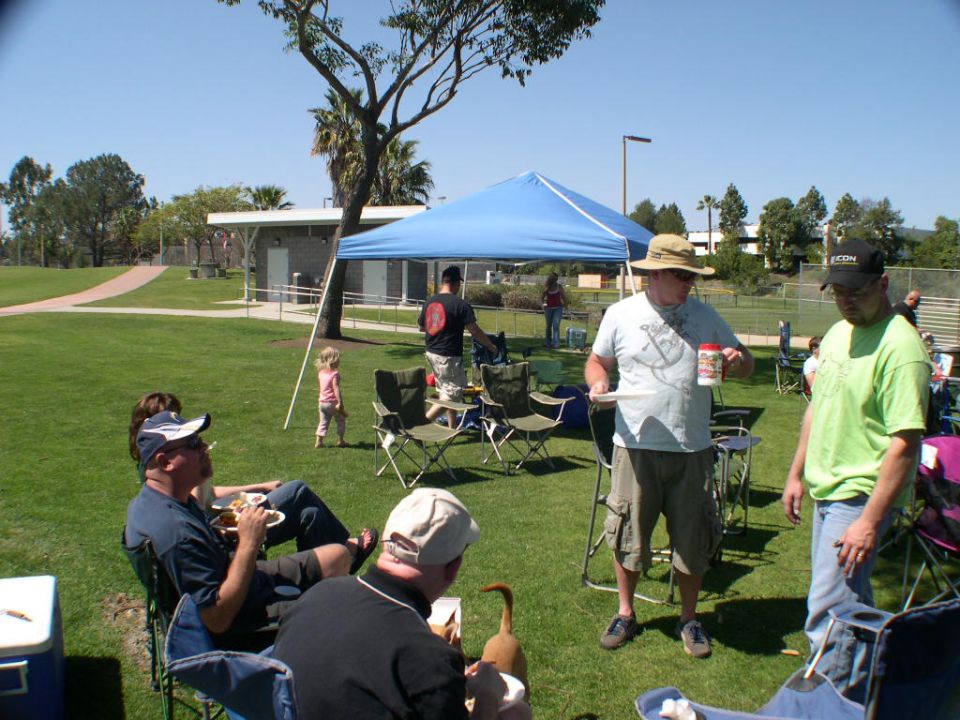 People gathered for a picnic in a park with a blue canopy