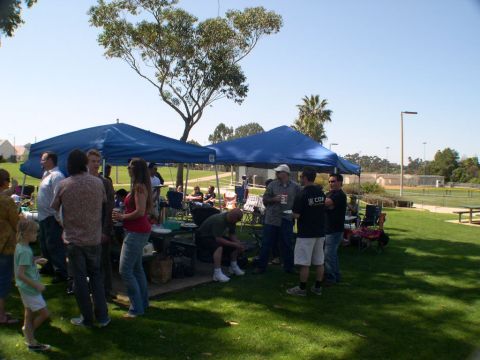 2007 Toyota FJ Cruiser - A group of people are socializing under blue tents in a park setting on a clear day.