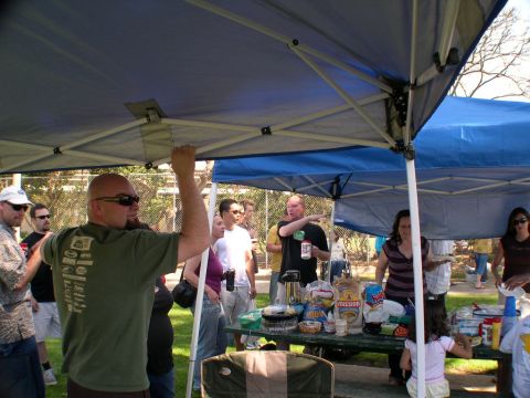 2007 Toyota FJ Cruiser - An outdoor gathering with people under tents and a picnic table filled with snacks and drinks.