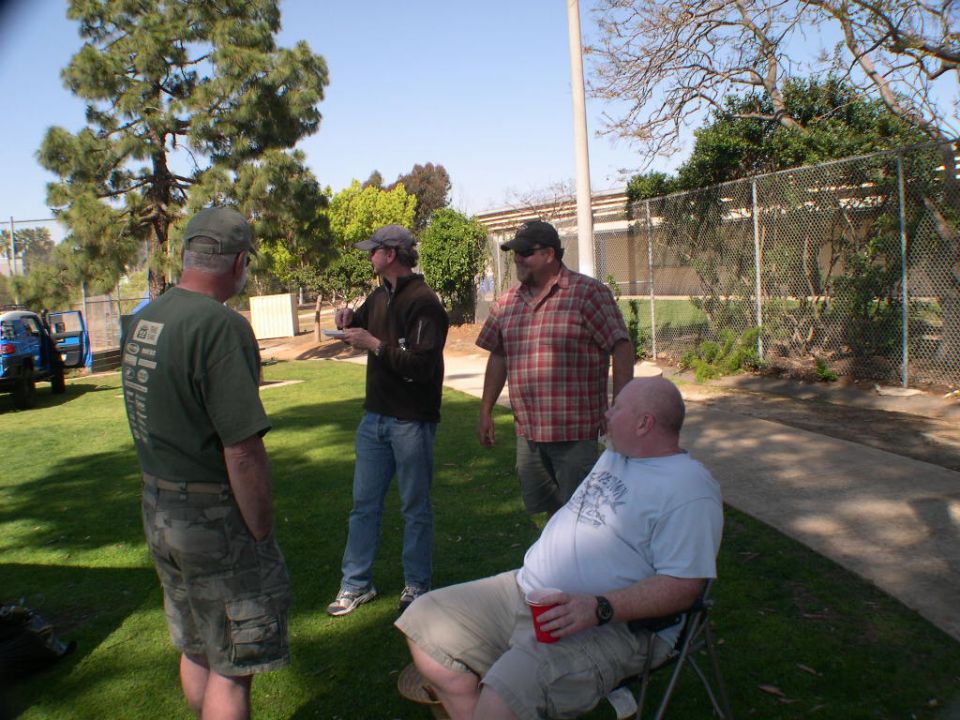 Four guys talking outside near a blue SUV