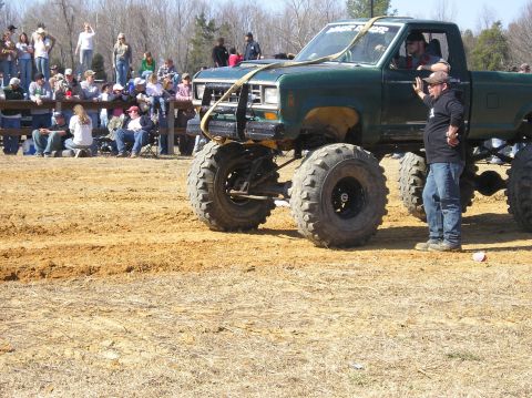 1993 Ford Bronco - Modified pickup truck with large tires and a roll cage, seen at an outdoor event with spectators.
